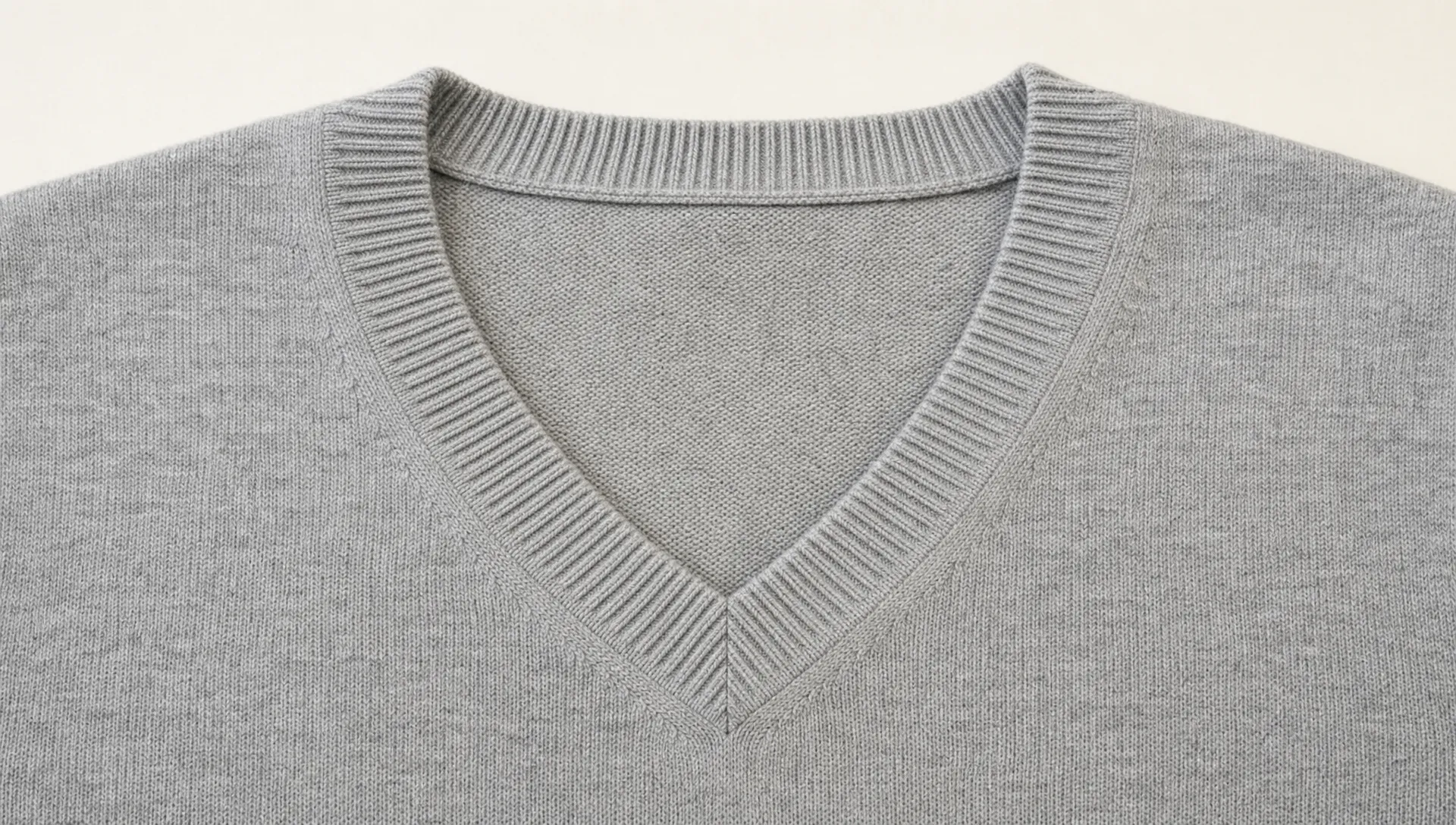 A merino V neck sweater neckline sample lies flat with the V point, rib width, shoulder points, and center-front miter visible for production review.
